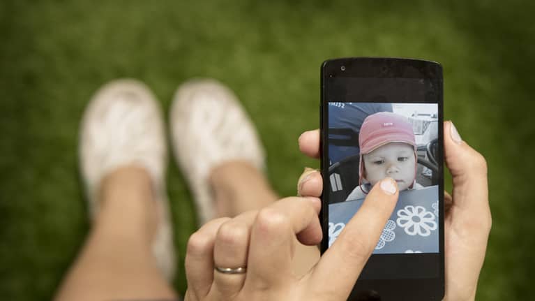 Äiti katsoo lapsensa kuvaa kännykästä.