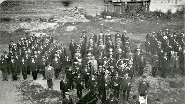 Punaisten juhla torvisoittokuntineen ja lippuineen.