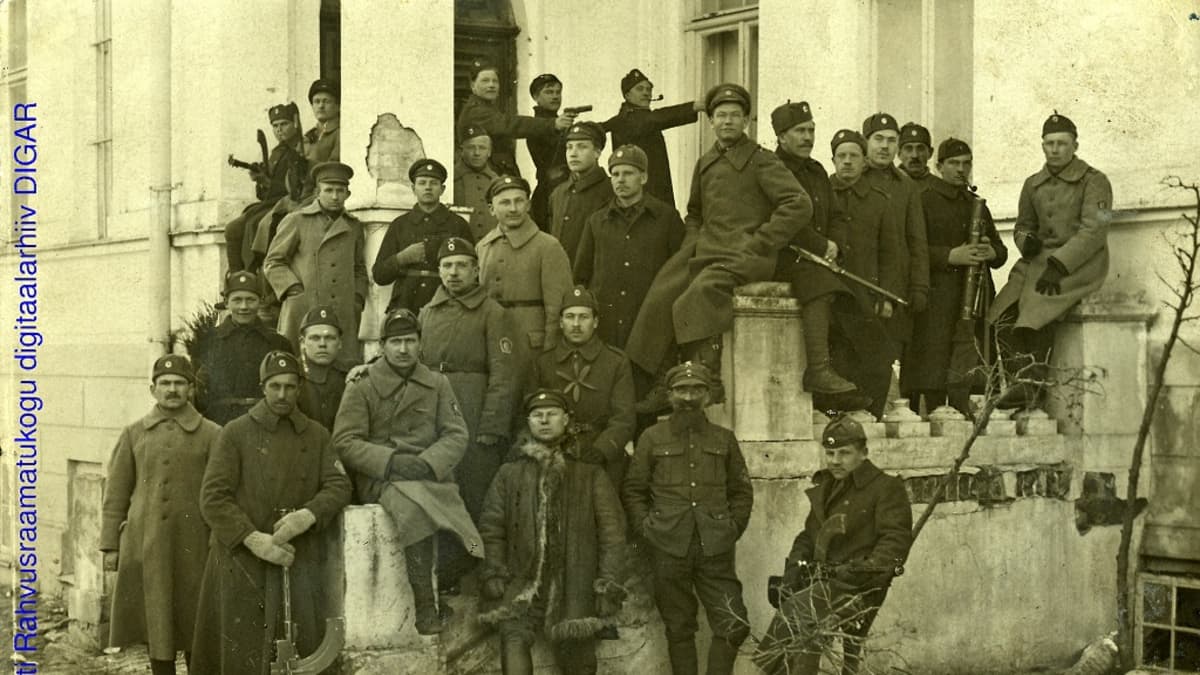Mustavalkoinen valokuva isosta miesjoukosta aseineen kartalon ulkoportailla.