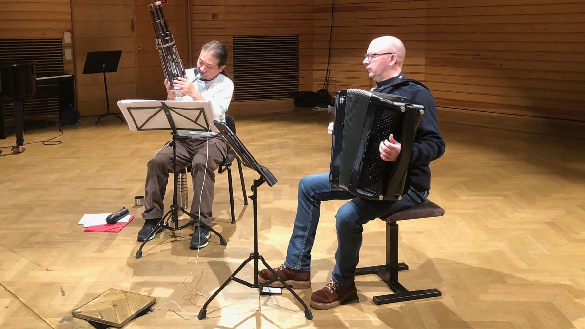 Kuvassa mies soittaa shengia ja toinen harmonikkaa