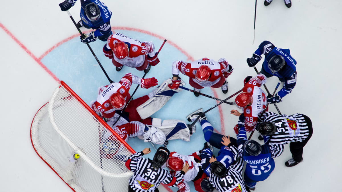 Tanskan maalivahti Frederik Andersen makaa jäällä Tanskan ja Suomen pelaajien ympyröimänä.