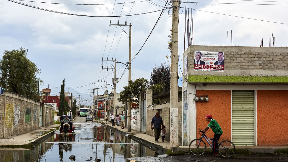 Jätevesi löyhkää kadulla San Juan Tezompan kylässä. Alueella ei ole kunnallista viemäröintiä. Kylässä lähes jokaisen talon seinällä roikkuu Andrés Manuel López Obradorin kannatuksesta kertova mainos.