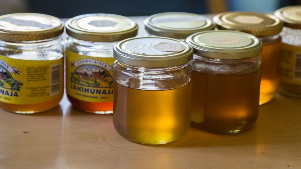 Erilaisia hunajapurkkeja pöydällä.