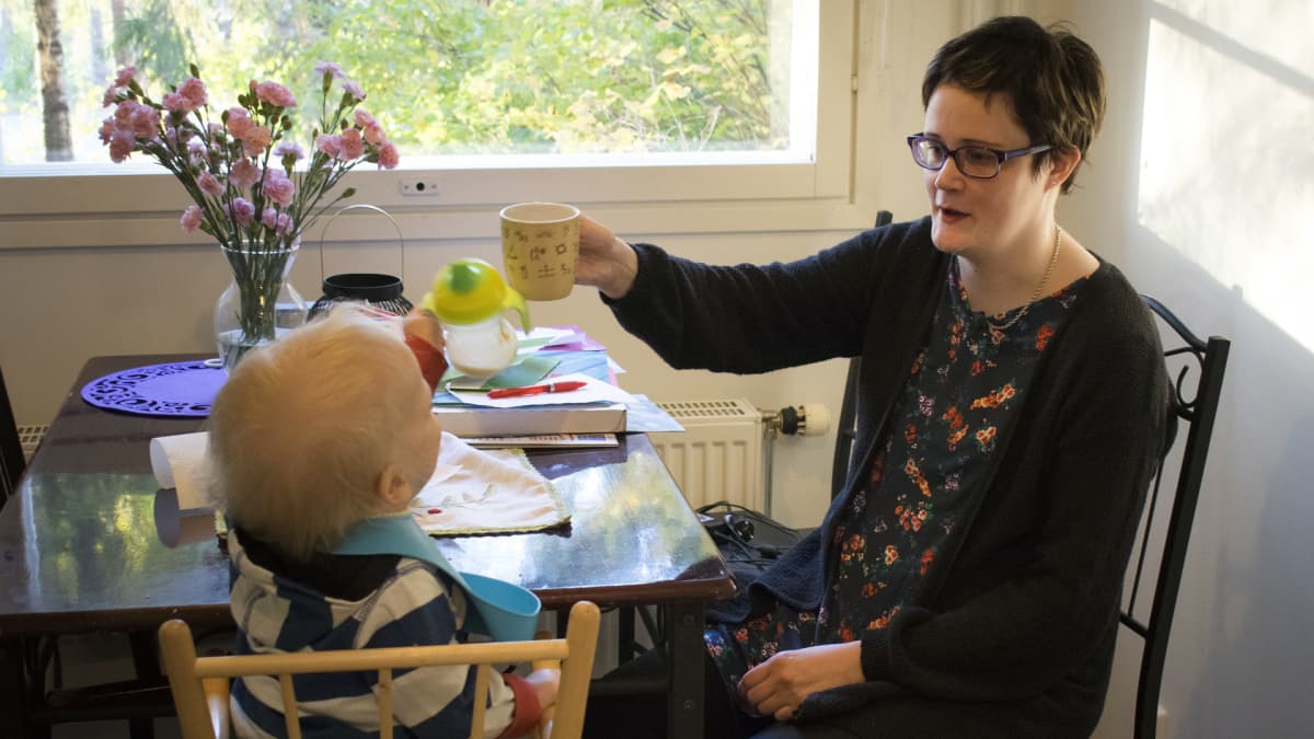 nainen ja pikkupoika skoolaavat kahvikupilla ja nokkamukilla aamiaispöydässä
