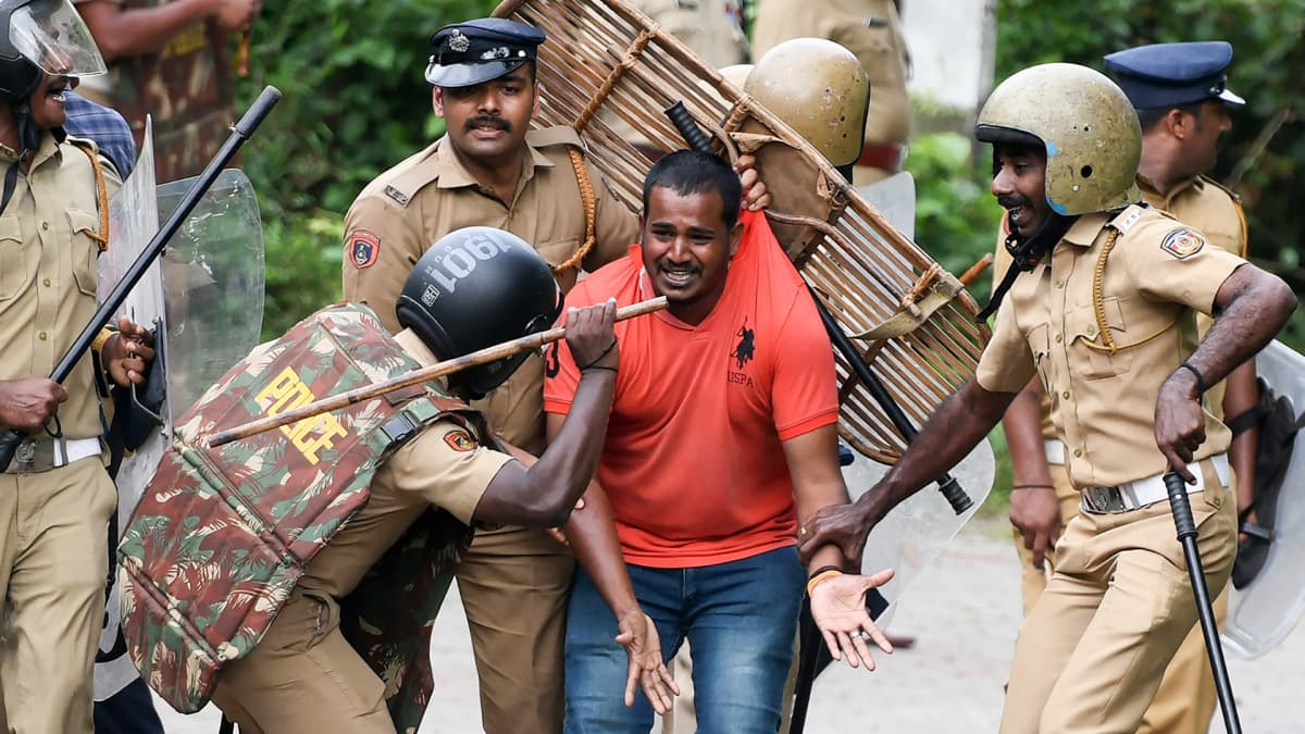 Intian poliisi hakkaa kepillä hinduaktivistiä muiden sotilaiden pidellessä aktivistia paikallaan.
