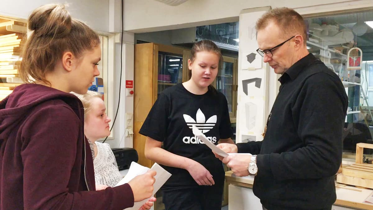 Käsityönopettaja Mika Leppiniemi opastaa tyttöjä teknisen työn suunnittelussa Kaarilan koululla.