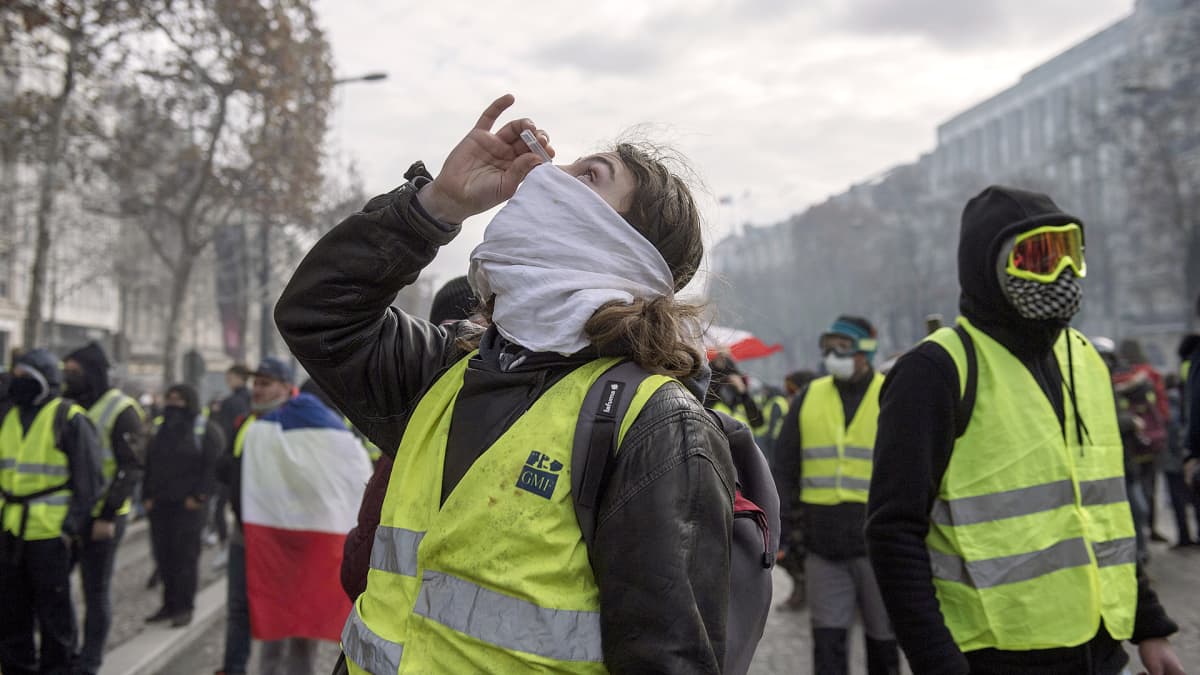 Keltaliivi-mielenosoittaja puhdistaa silmiään silmätipoilla Pariisissa 8. joulukuuta.