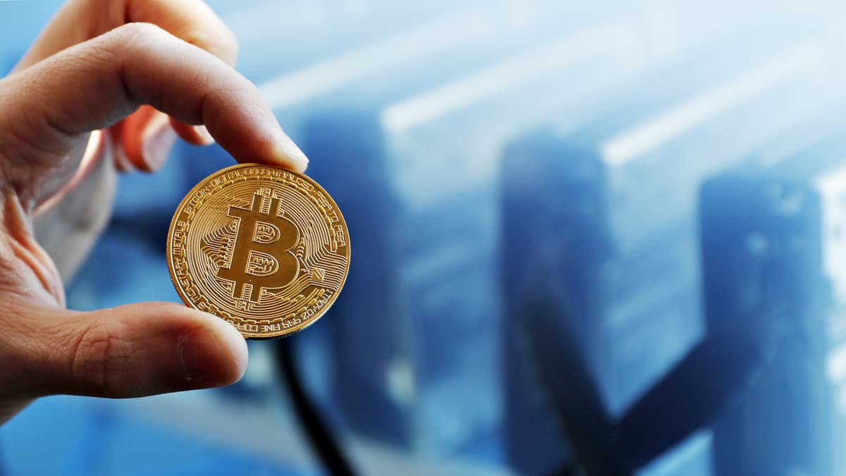Bitcoin -kolikko miehen vasemmassa kädessä.