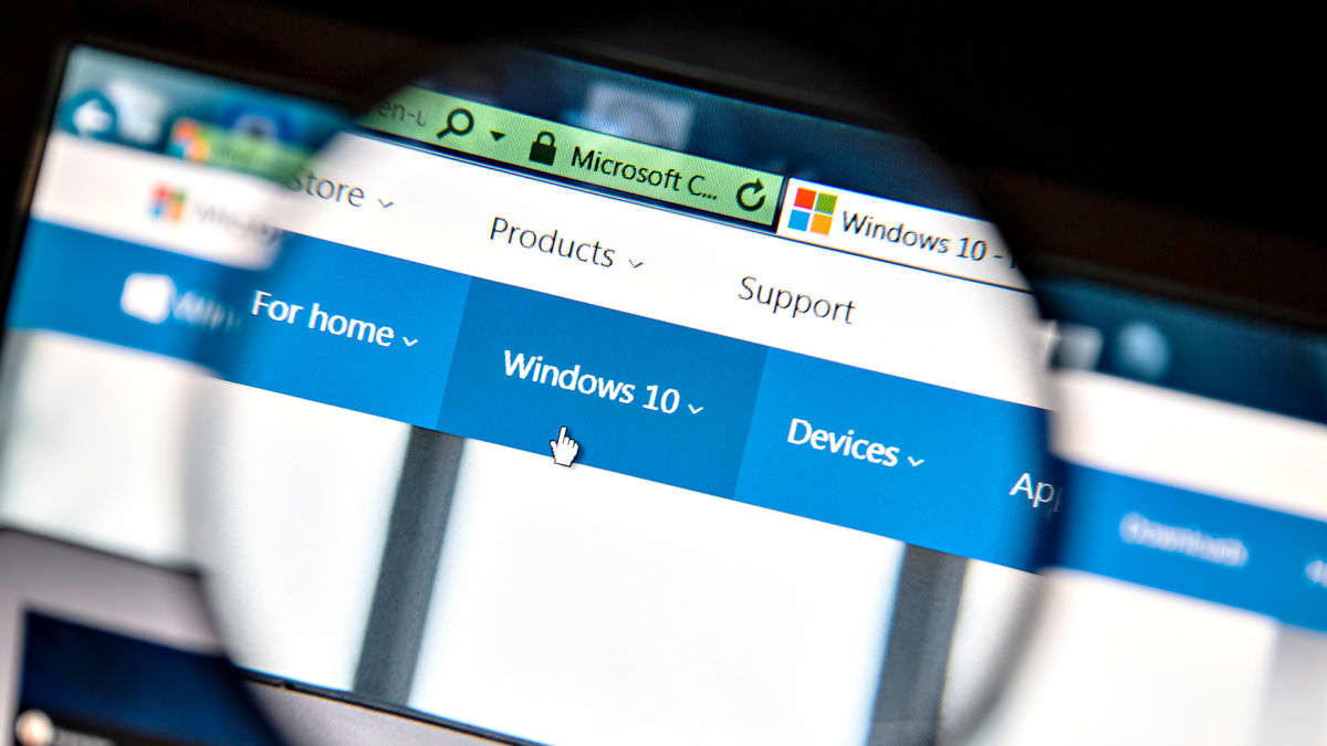 Suurennuslasin läpi näkyy tietokoneen näytöllä Windows 10:n alavalikko ja käsi-ikoni.