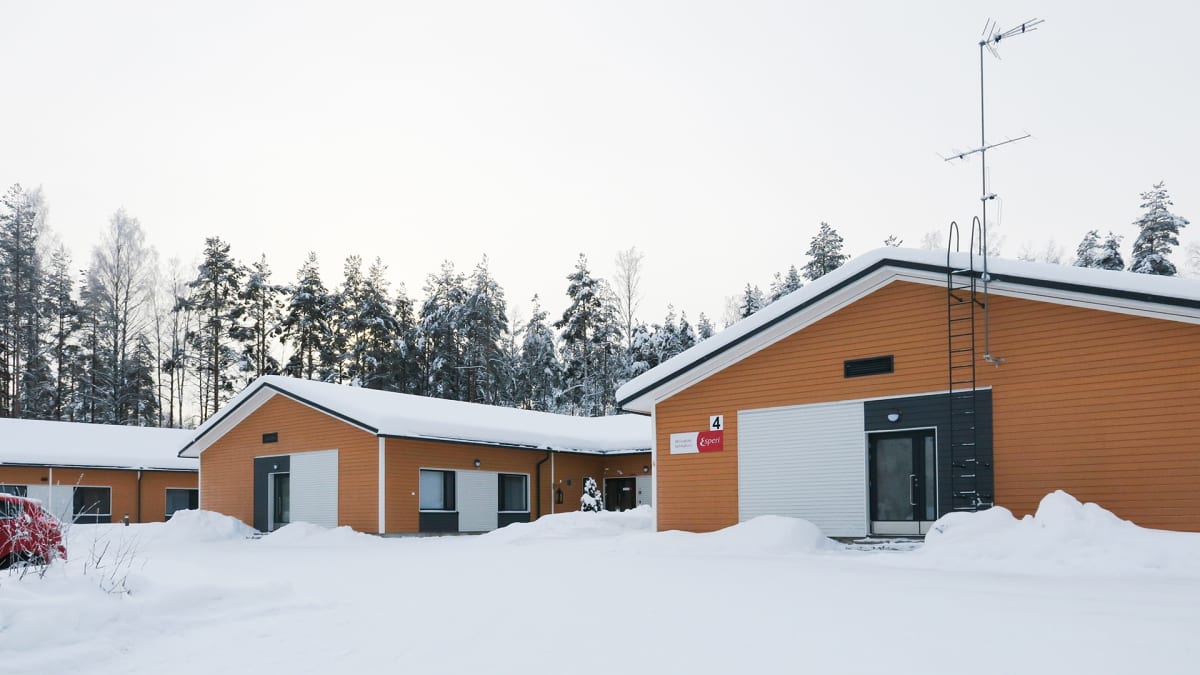 Kolme oranssiksi maalattua hoivakotirakennusta rinnan lumisella pihalla.