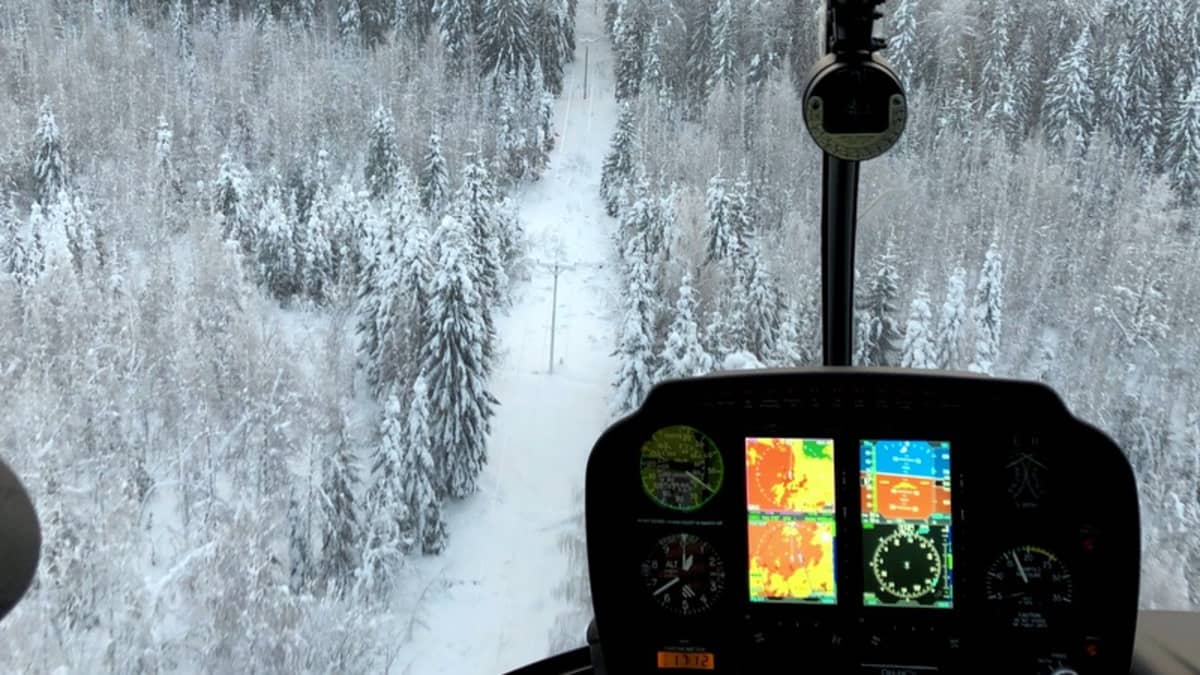 Helikopteri lentää sähkölinjan yllä.