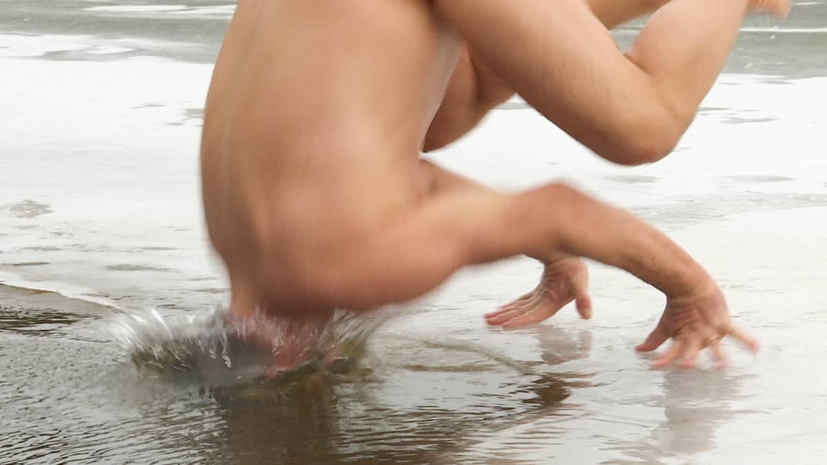 Joogaohjaaja Magnus Appelbergin bakasana eli tasapainoilu suorilla käsivarsilla päättyy pulahdukseen avantoon, pää on jo vedessä, pärskeitä kaulan ympärillä.