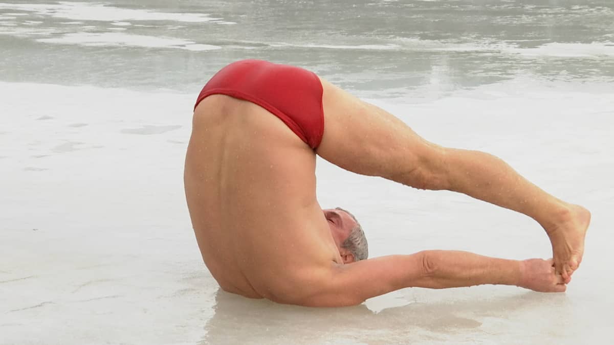Joogaohjaaja Magnus Appelberg tekee supta konasanan (selinmakuulla suorat jalat ja suorilla käsillä varpaista kiinni) vetisellä jäällä.