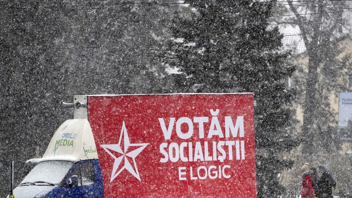 Pakettiauto ajaa lumisateessa sosialistien vaalijulistetta kuljettaen.