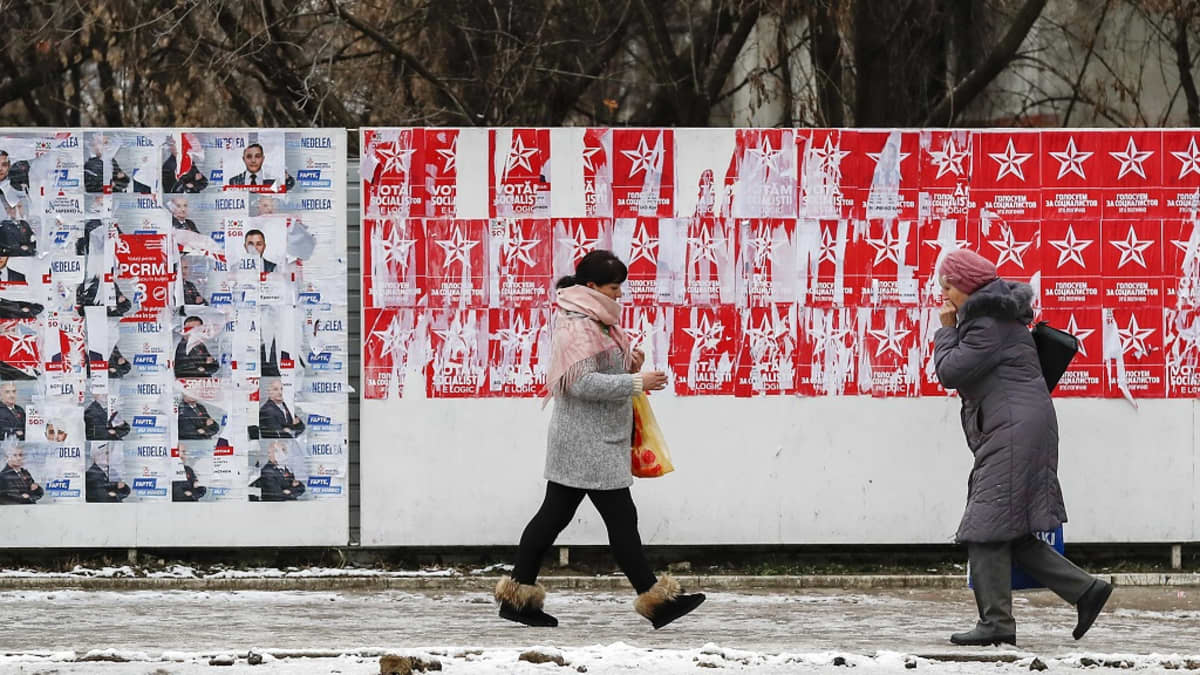 Kaksi naista kävelee vaalijulisteiden ohi talvisella kadulla.