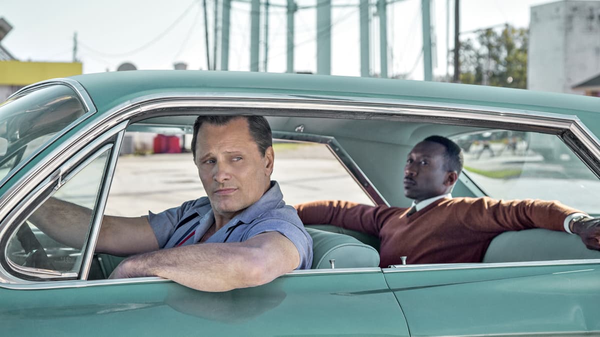 Näyttelijät Viggo Mortensen ja Mahershala Ali Green Book -elokuvassa. Elokuvastillissä valkoinen mies toimii autonkuljettajana mustalle pianistille 1960-luvun Yhdysvalloissa.