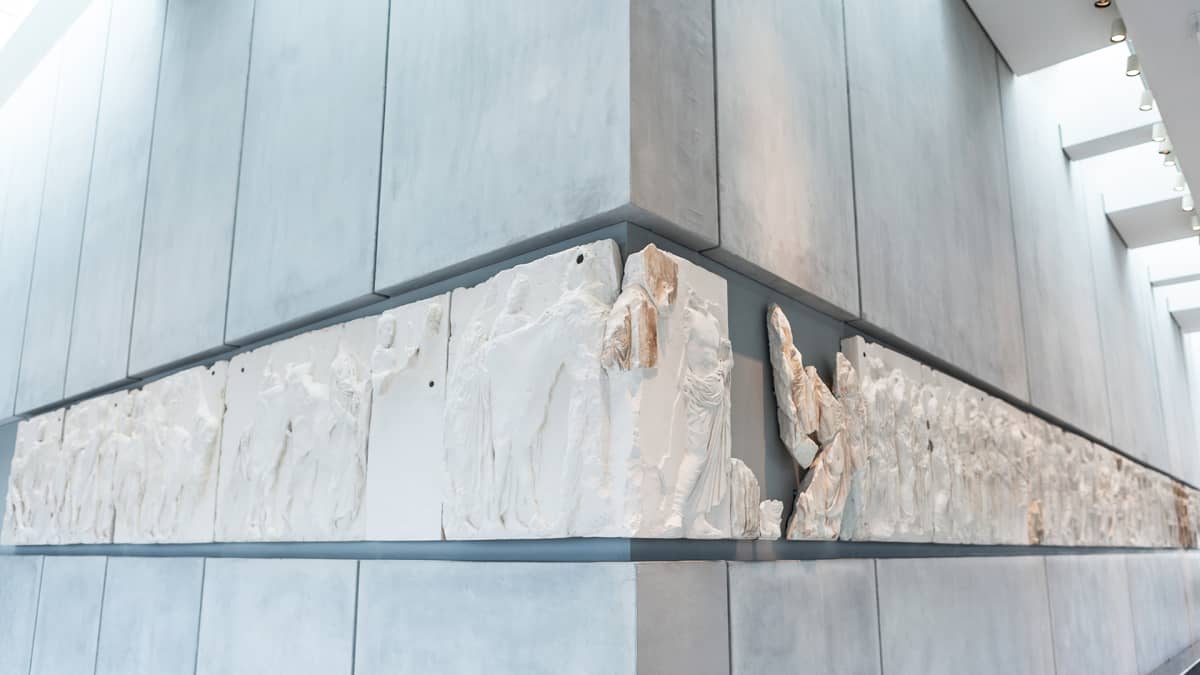 Parthenonin metrin korkuinen marmorifriisi kuvaa antiikin Panathenaia-juhlakulkuetta ratsumiehineen, juhlan osanottajineen ja uhrieläimineen. Valkoiset osat ovat Lontoon British Museumissa.