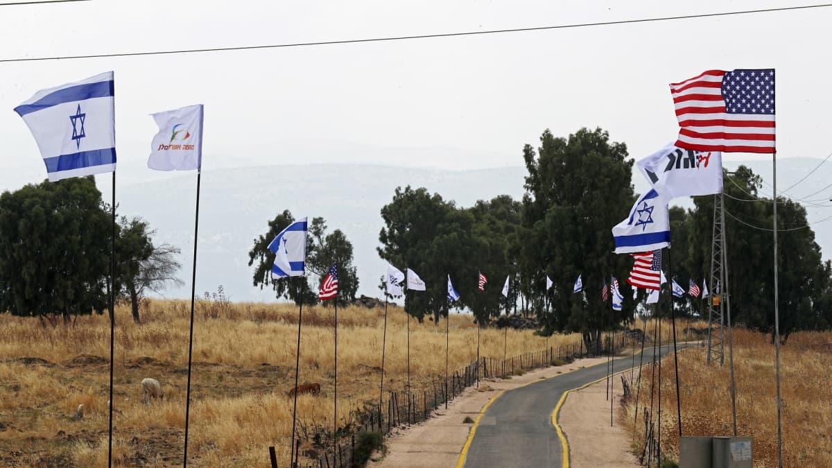 USA:n ja Israelin liput liehuvat tien varsillla.