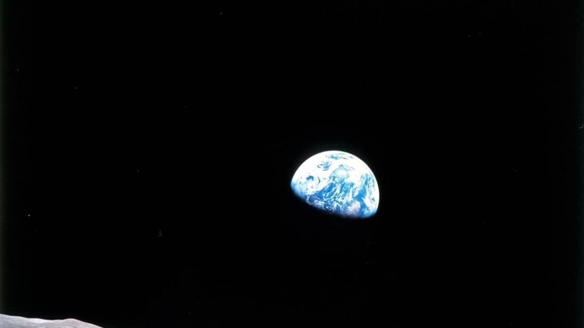 Kuun pintaa ja takana pimeydessä osa sinisestä maapallosta. 