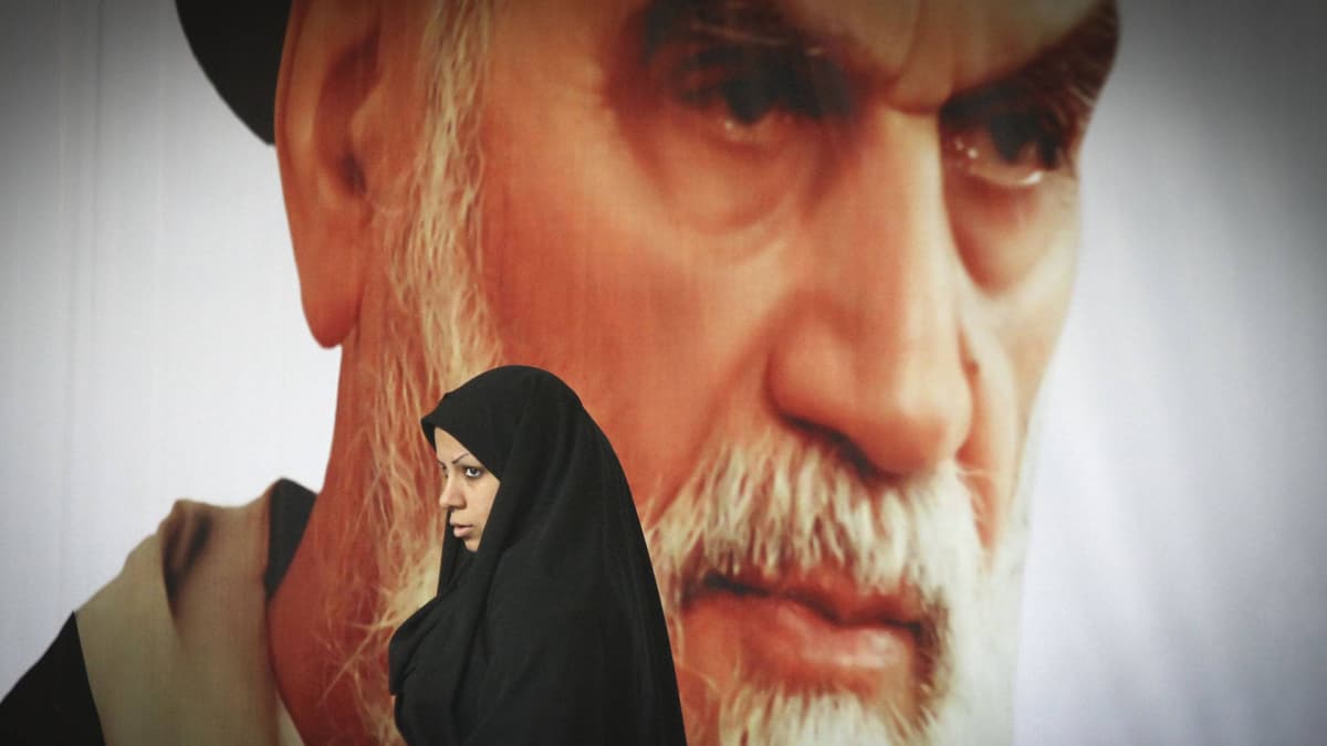 Nainen kävelee suuren Ayatollah Ruhollah Khomeini kuvan ohitse.