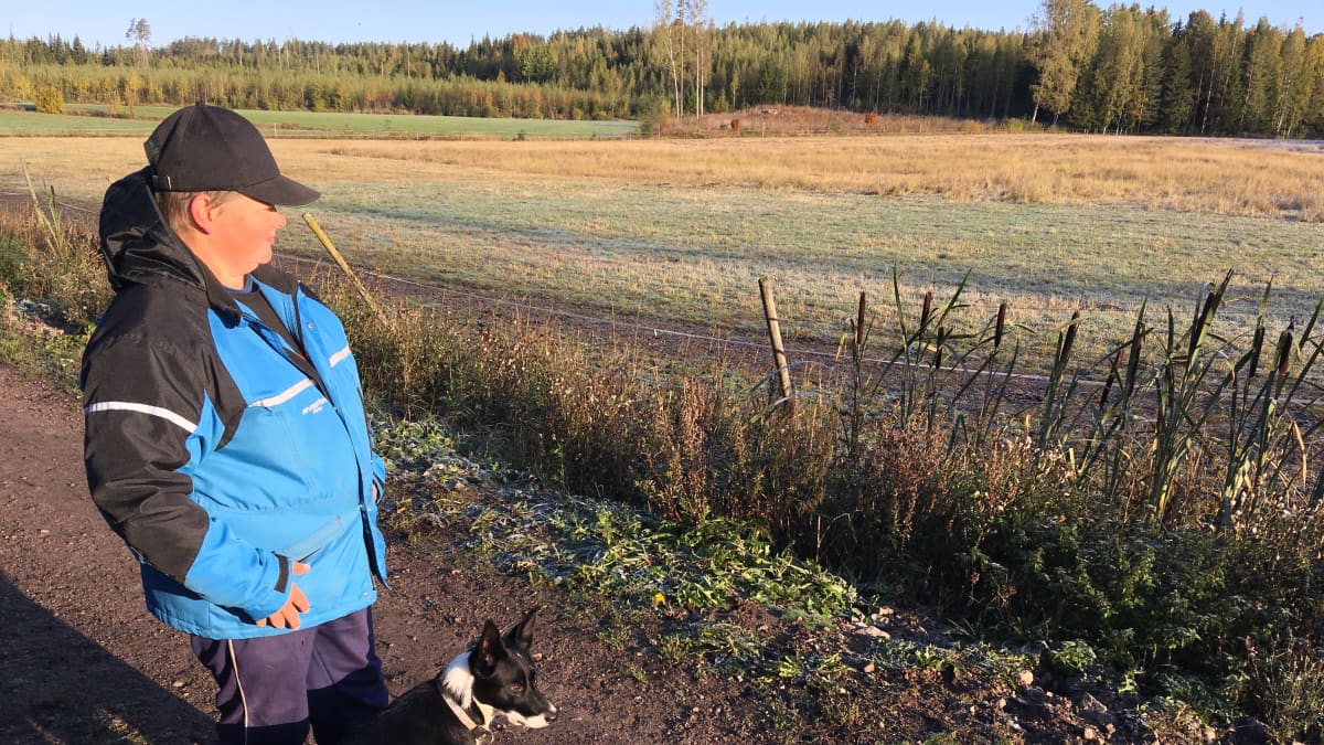 Pirjo Vanhala seisoo koiransa kanssa lammasaitauksen vieressä