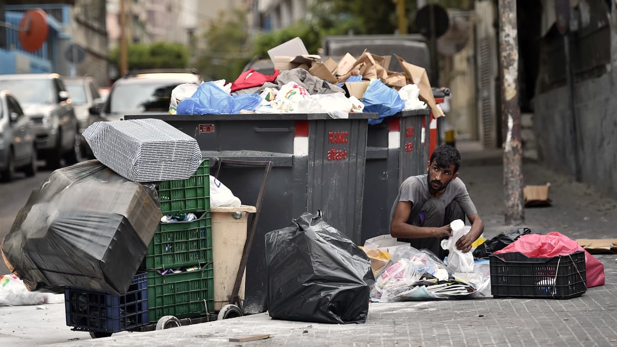 Mies käy läpi roskia kadulla Beirutissa.