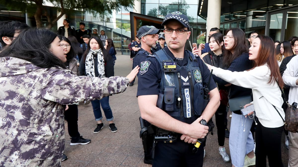 Australian poliisi seisoo protestoijien välissä.