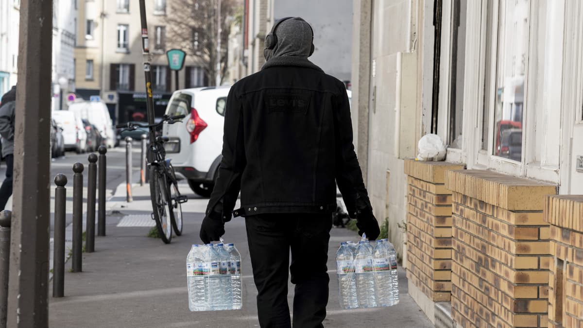 Mies kantaa vesipulloja kadulla.