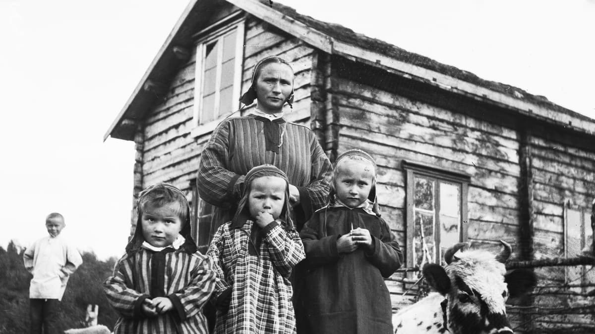Inarilaisia pikkutyttöja ja heidän äitinsä kodin pihalla.