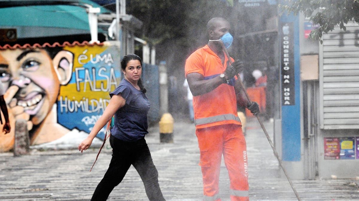 Hengityssuojaan pukeutunut mies lakaisee katua Rio de Janeirossa.