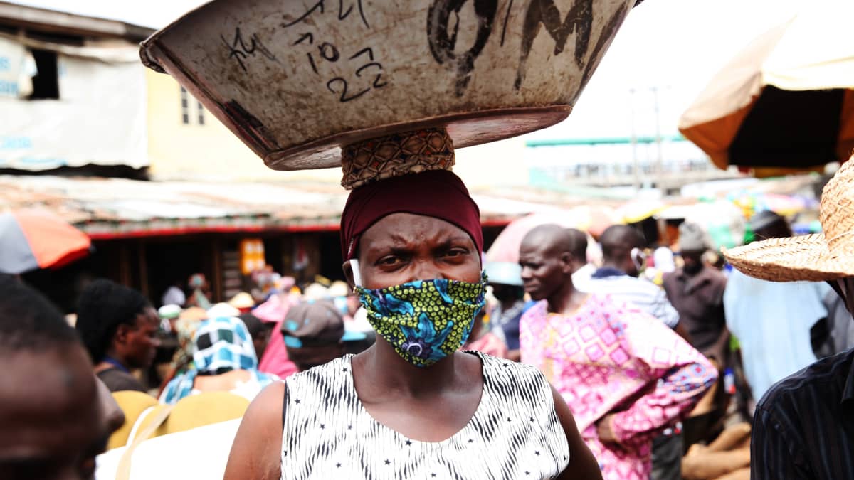 Kuvassa on hengityssuojaa käyttävä nainen nigerialaisella torilla.