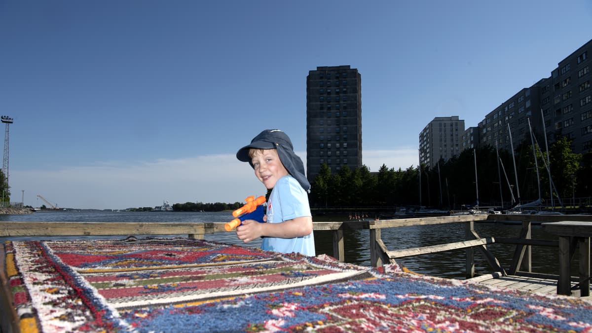 Lapsi pesee mattoa vesipyssyllä mattolaiturilla Merihaassa.