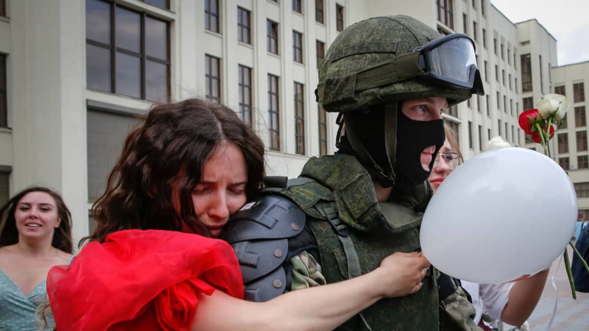 Mielenosoitukseen osallistunut nainen halasi sotilasta Minskin itsenäisyyden aukiolla perjantai-iltana.