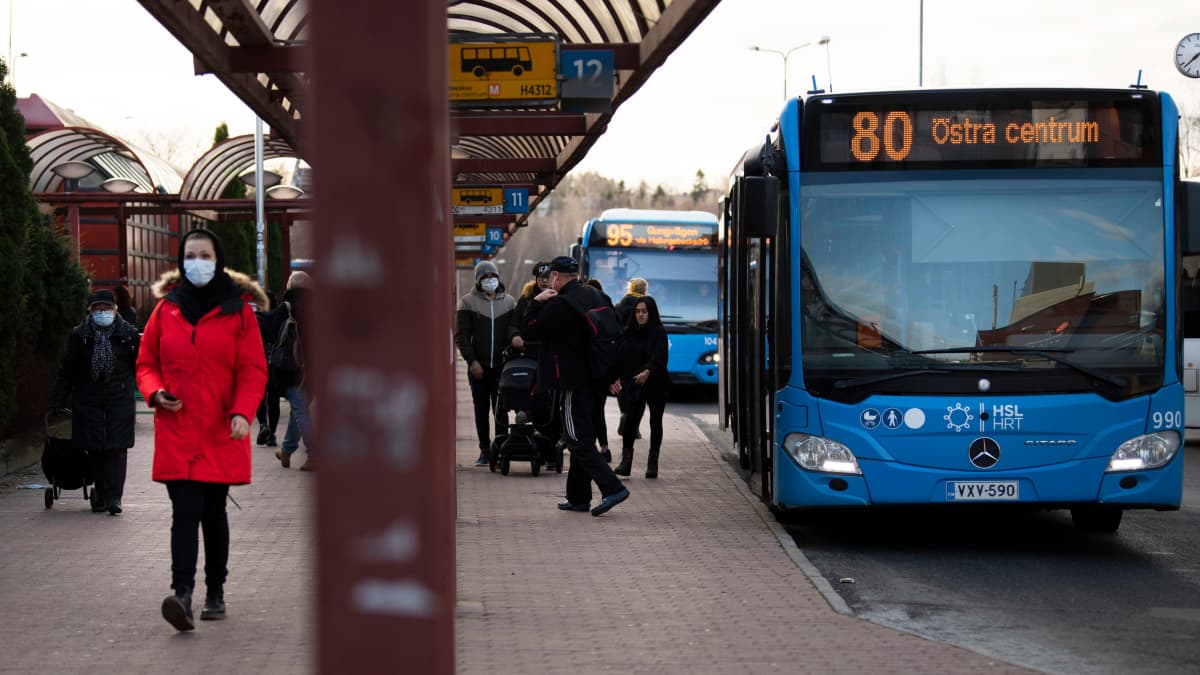 Kasvomaskeihin pukeutuneita matkustajia Itäkeskuksen bussiterminaalin edustalla.