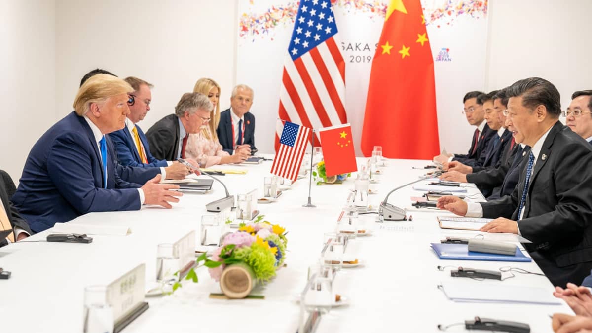 Trump ja Xi seurueineen istuvat pöydän ääressä. 