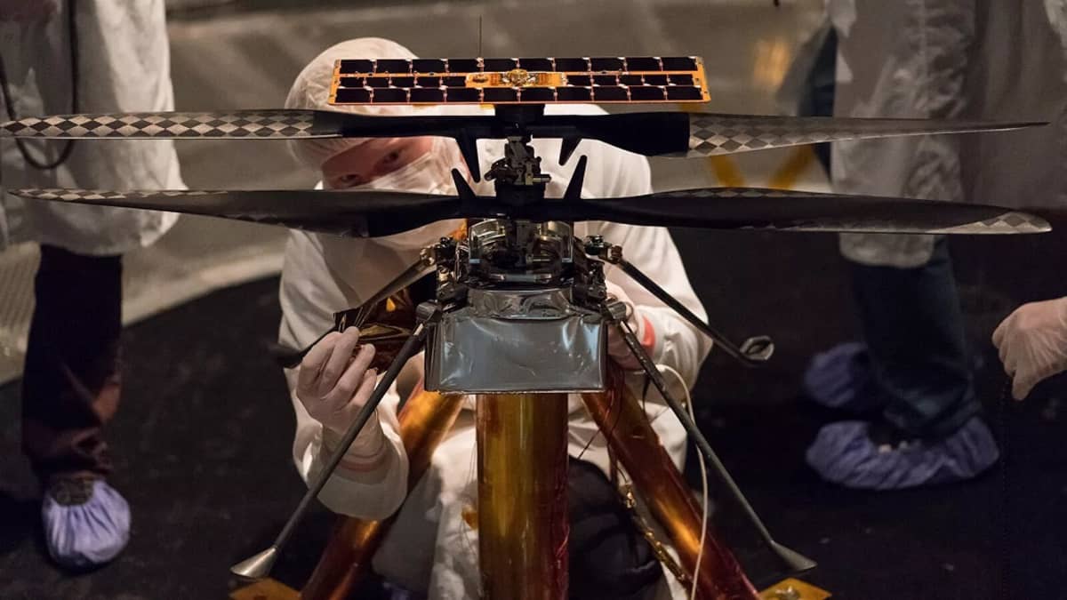 Suojavaatteisiin pukeutunut tutkija säätää pientä helikopteria.