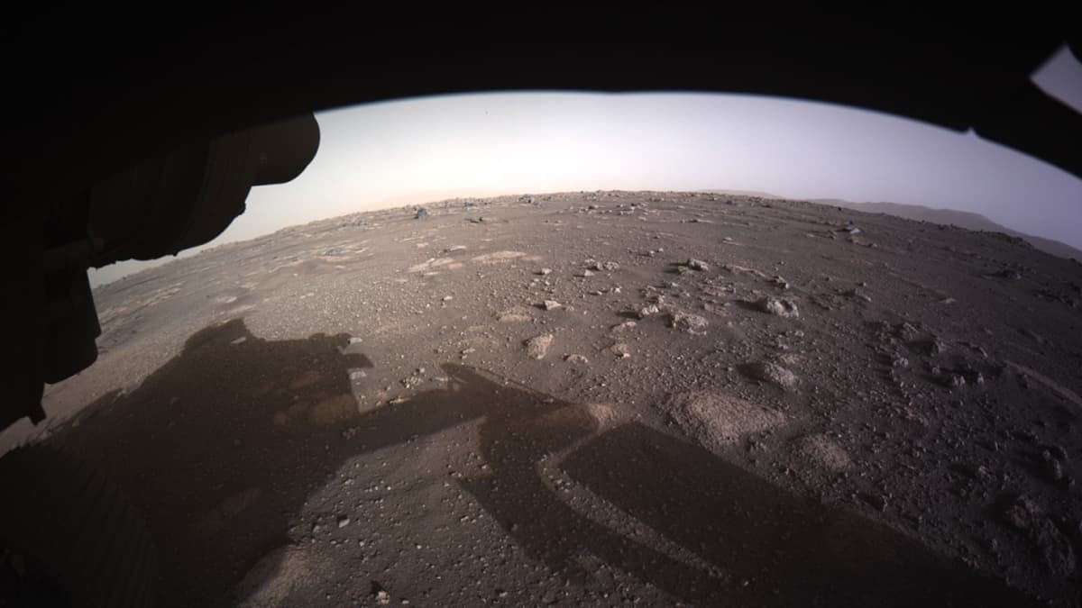 Marsin punainen pinta, jolle heijastuu mönkijä ja sen robottivarsi. 