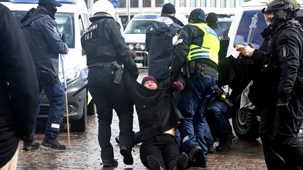 Poliisit raahaavat mielenosoittajaa Kauppatorilla.