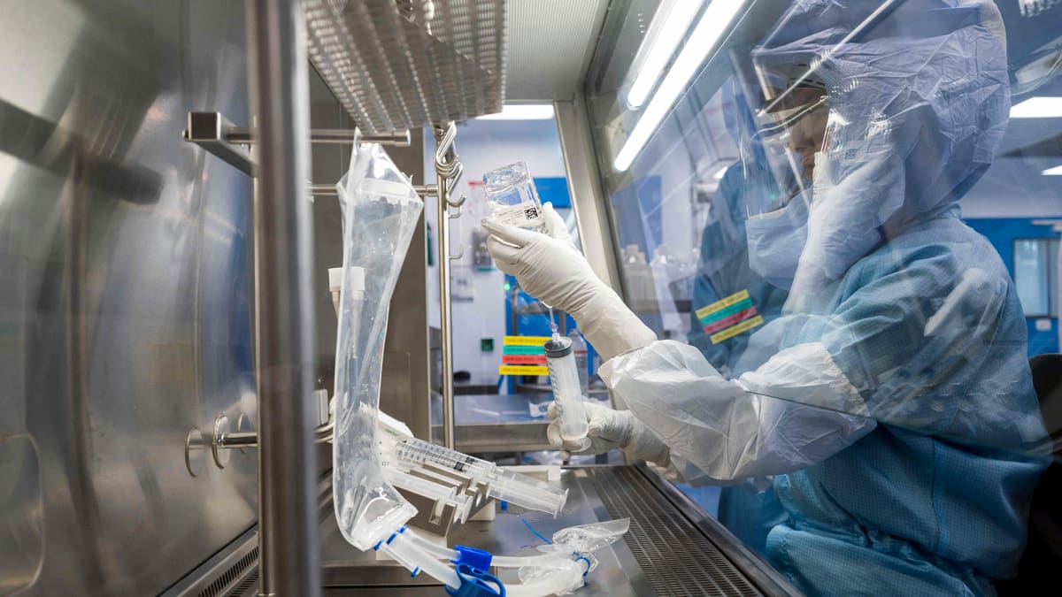Suojavarusteisiin pukeutunut työntekijä testaa koronarokotteen valmistusmenetelmää laboratoriossa.