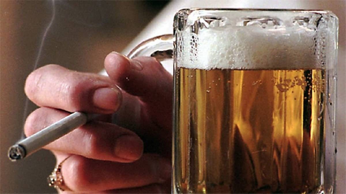 Kuvassa oluttuoppi ja savuketta pitelevä käsi.