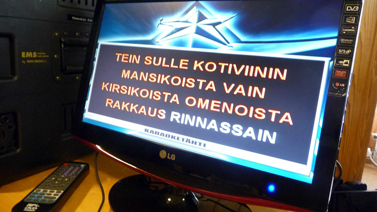 Lähikuvassa karaokelaitteen näytöllä kotiviini-kappaleen sanoja.