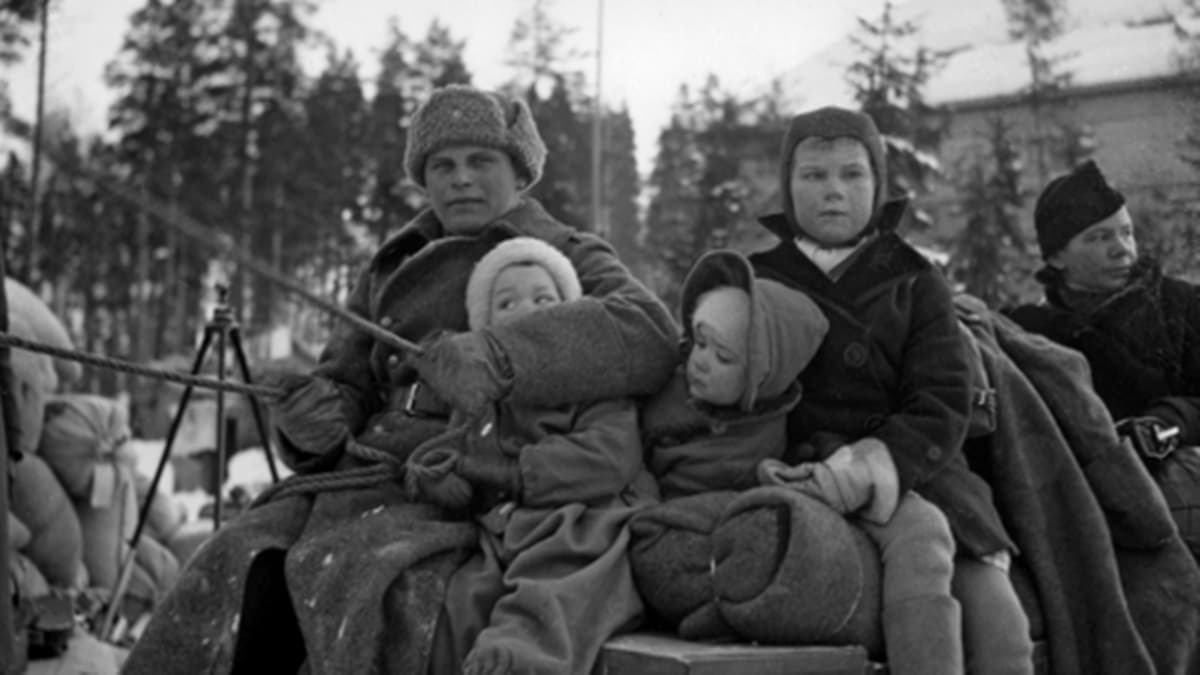 Sotilas hevoskuorman ohjaksissa ja evakuoituja karjalaisia lapsia sekä nainen muuttokuorman päällä istumassa evakkomatkalla. 