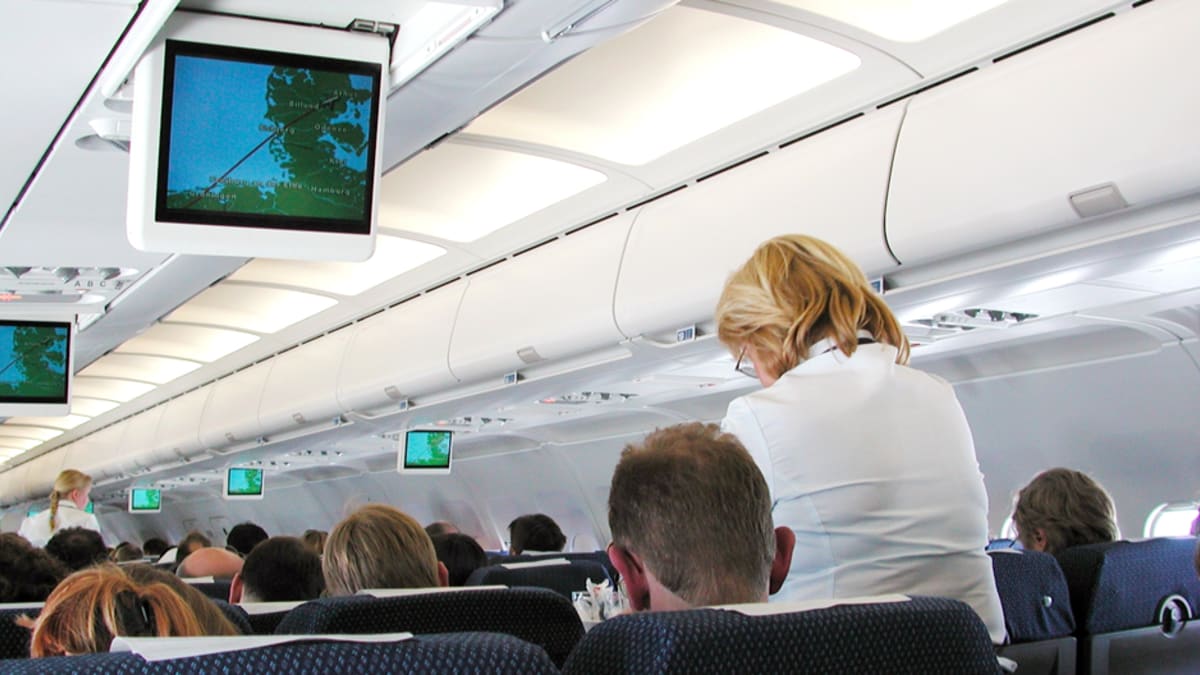 Lentoemäntä tarjoilee matkustajille lentokoneessa matkan aikana.