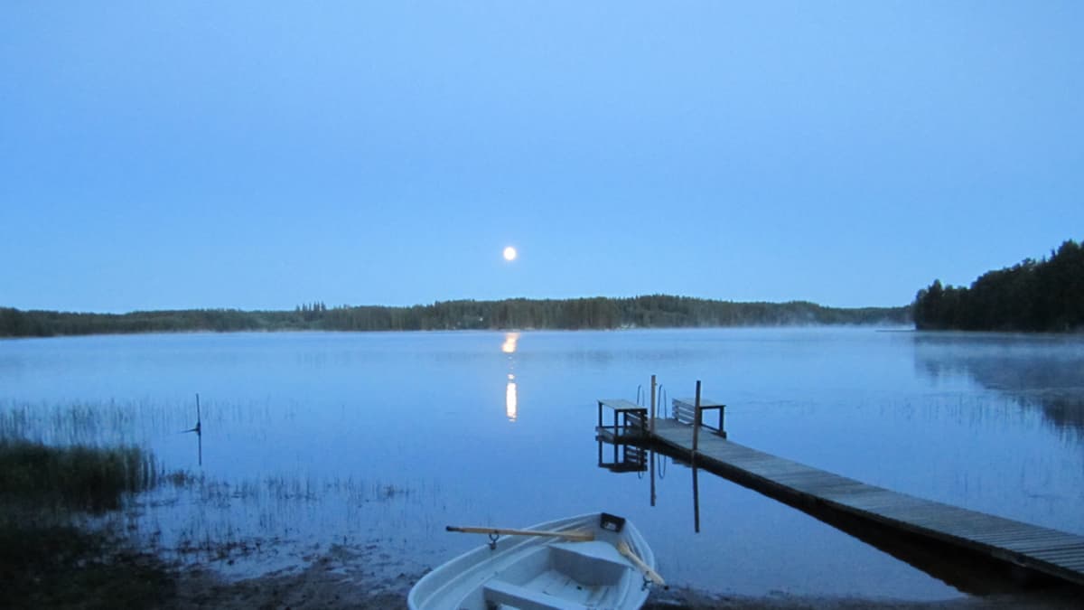 Vene ja laituri järven rannalla iltahämärässä.