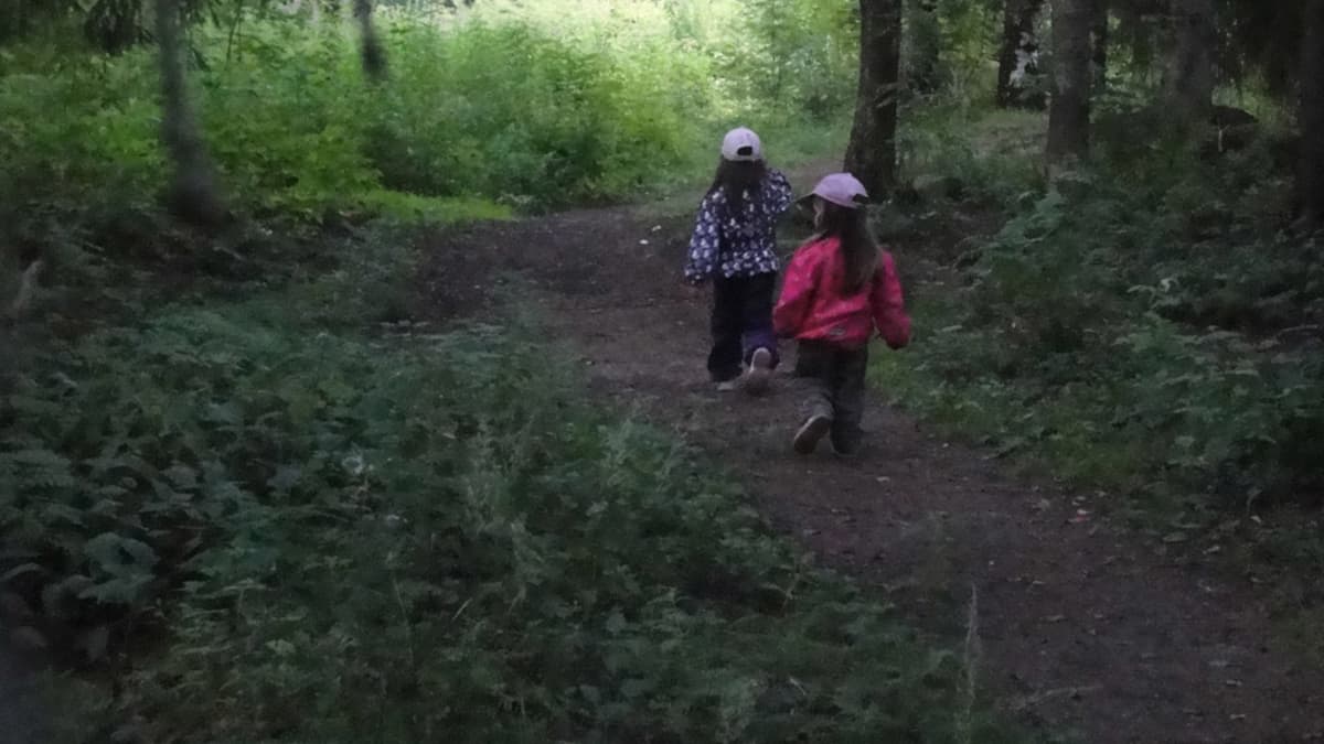 Kaksi pientä tyttöä kävelyllä metsässä.