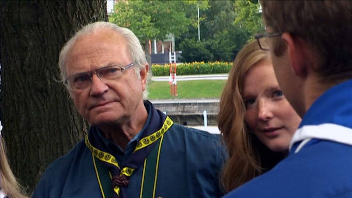 Kuningas Kaarle XVI Kustaa partioasu päällään kuuntelee suomalaisia partiolaisia.