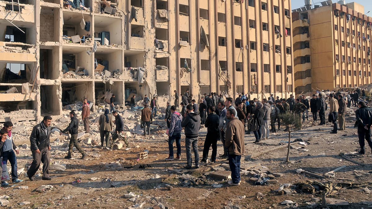 Ihmiset tutkivat pommi-iskun aiheuttamia tuhoja Aleppon yliopiston edustalla.