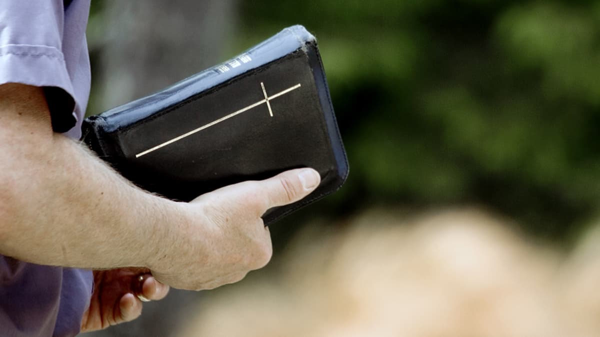 Pappi kädessään raamattu.
