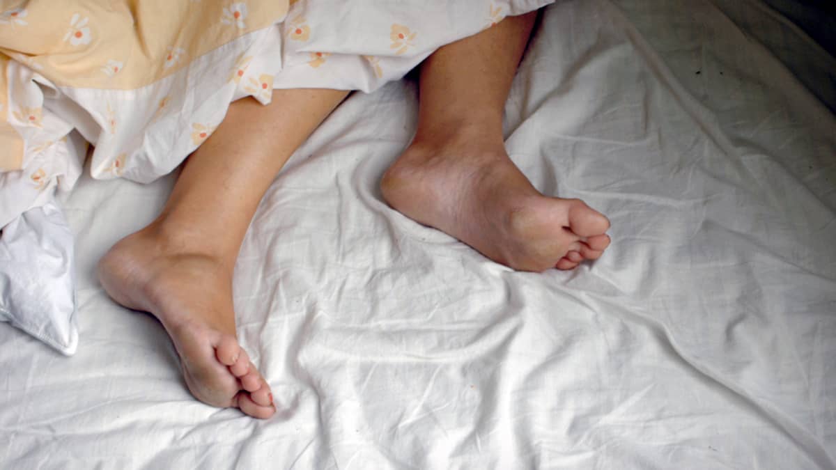 Nukkuvan naisen jalat näkyvät peiton alta.