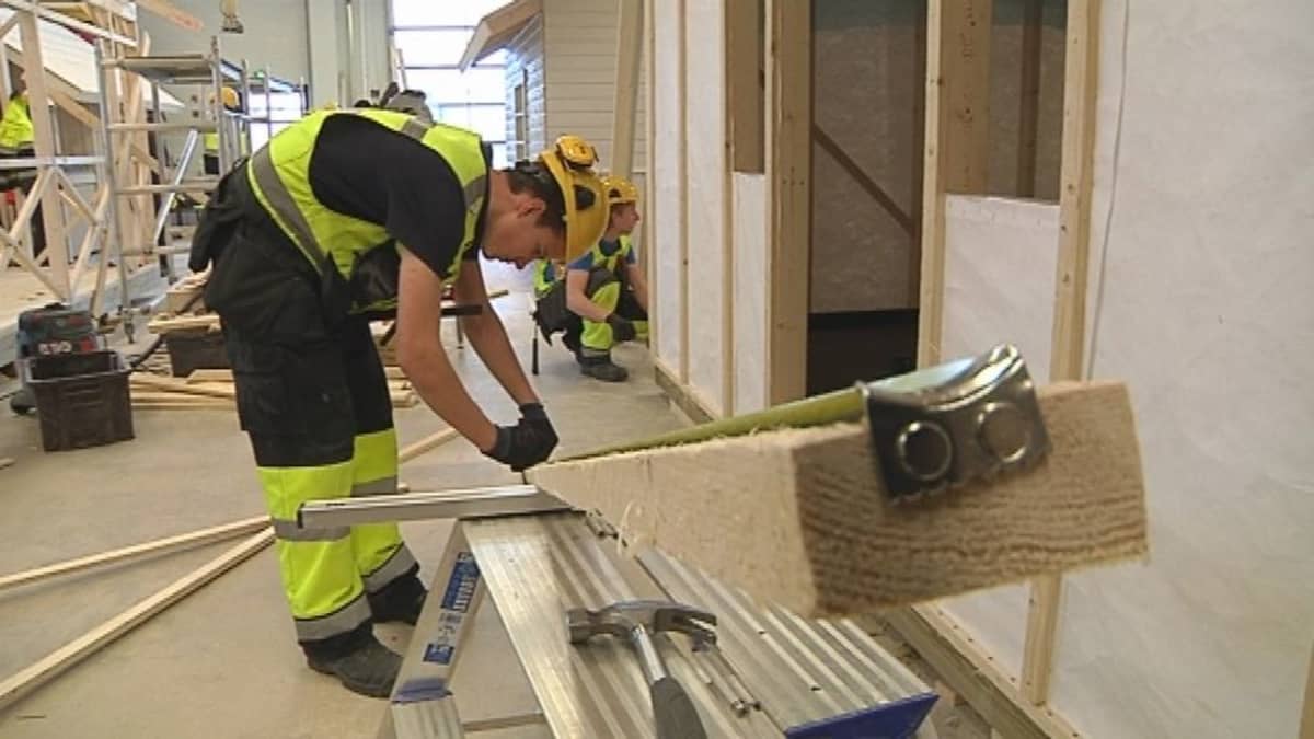 Ammattikoulussa rakennusalaa opiskeleva poika mittaa lautaa.